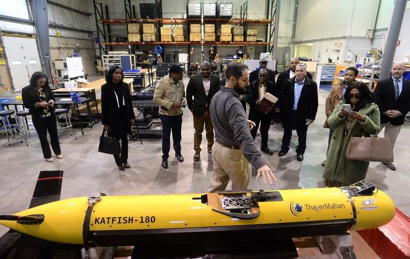 Members of a delegation from Kingston, Jamaica, and officials from Groton and New London listen to Greg Sabra, center, director of shore energy, talk about the Sea Scout while visiting ThayerMahan in Groton on Friday, Dec. 6, 2019, during a tour of both cities. The groups are in an exploratory process to investigate a possible sister city relationship. (Dana Jensen/The Day)
